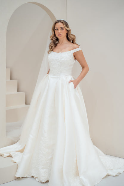 Woman in a white wedding dress standing in a softly lit room with neutral tones