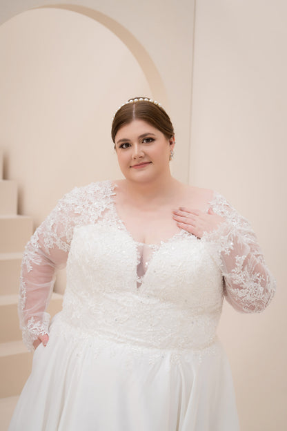 Woman wearing a white wedding dress with lace sleeves in an elegant indoor setting