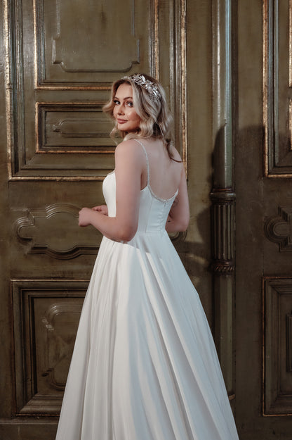 Woman in a white wedding dress standing in front of a ornate wooden door