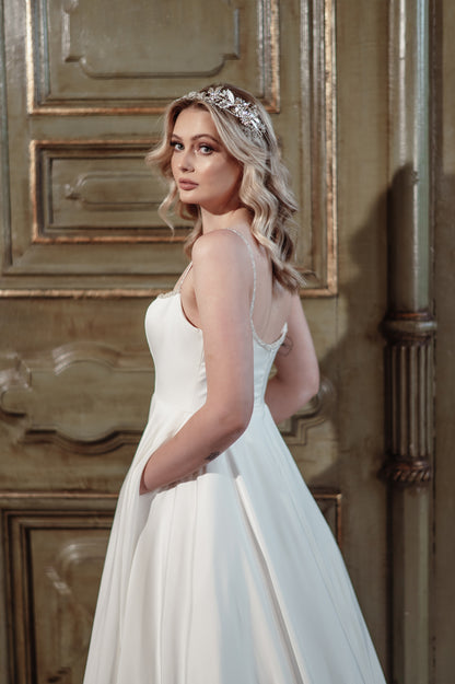 Woman in a white wedding dress with sheer sleeves standing against an ornate wooden door