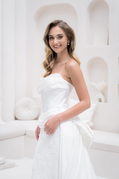 Woman in a white strapless dress standing against a white background