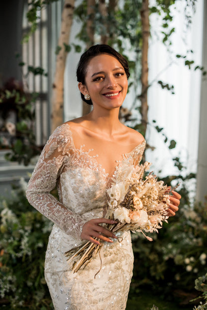 Woman in a wedding dress holding a bouquet of flowers in a decorated indoor setting.