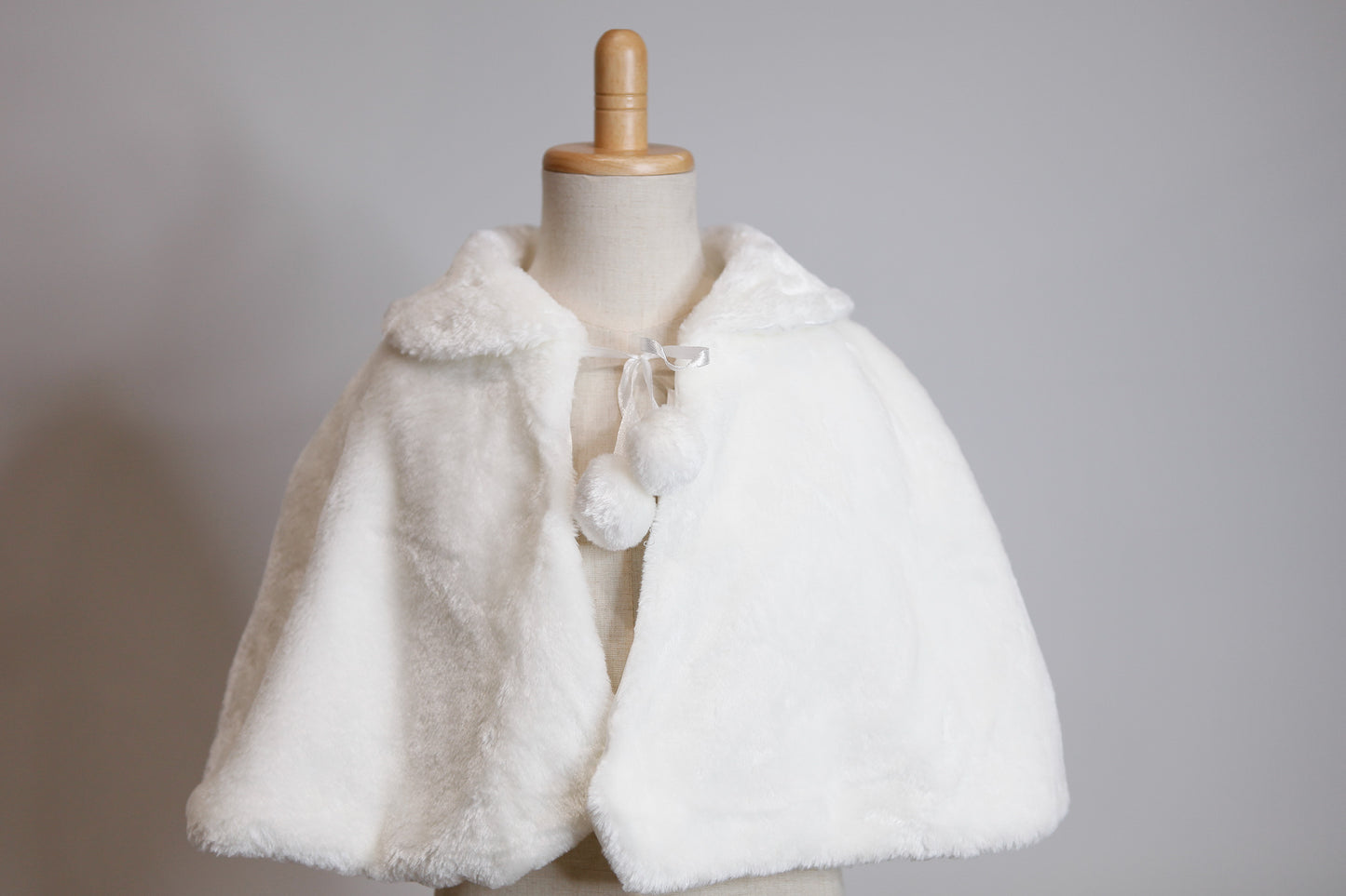White fur shrug on a mannequin against a gray background