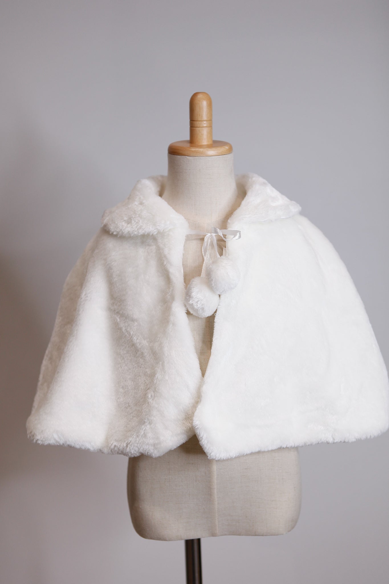 White fur cape on a mannequin against a gray background
