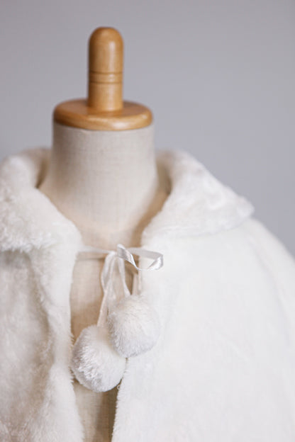 White fur coat on a mannequin with a wooden head against a gray background