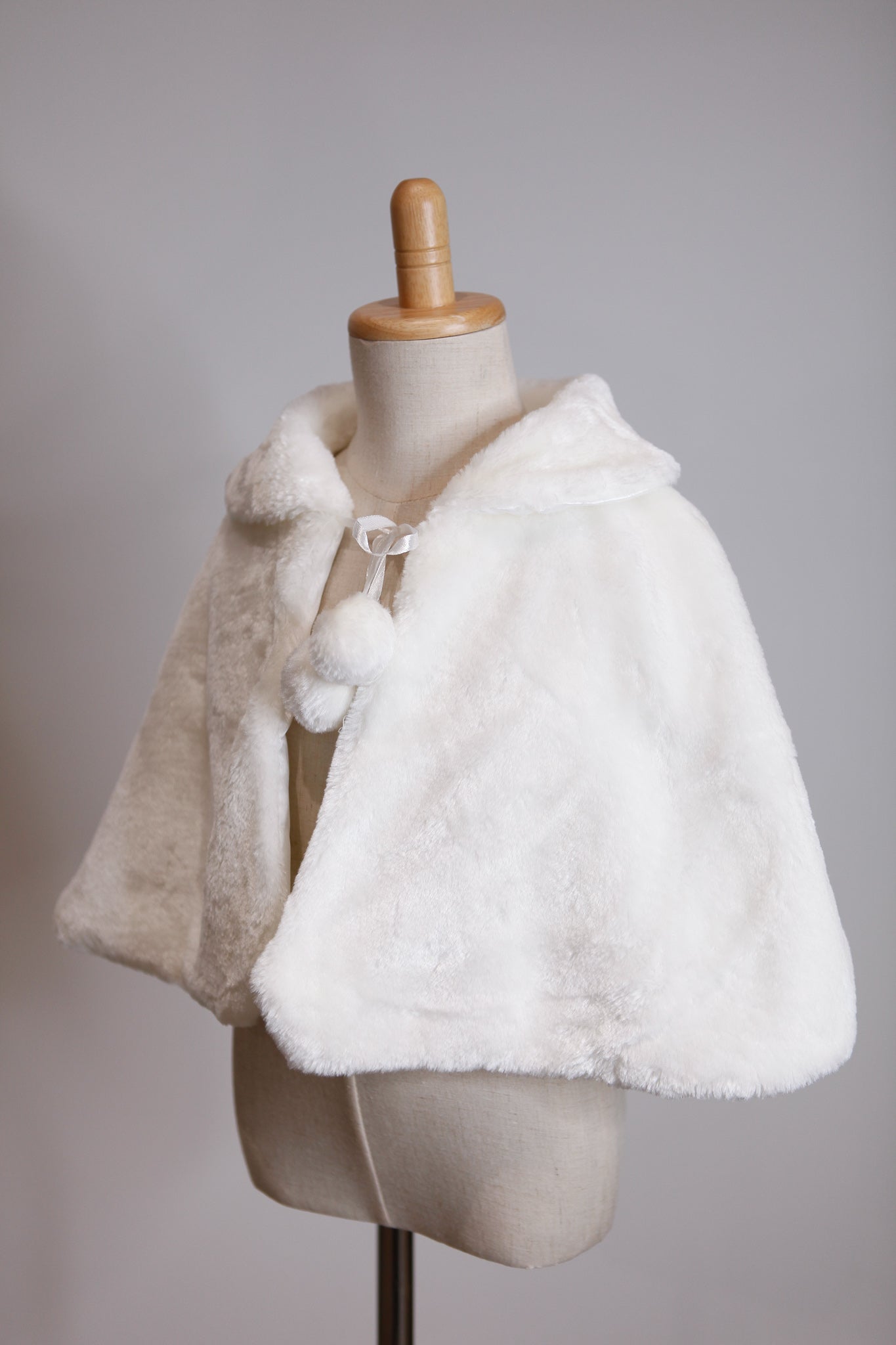 White fur cape on a mannequin against a gray background