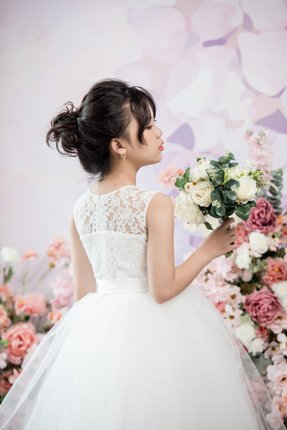 Woman in a white wedding dress holding flowers against a floral background