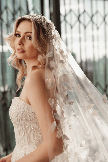 Woman wearing a wedding dress with a floral veil indoors.