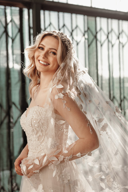 Bride wearing a lace veil with floral details in front of a decorative metal gate.