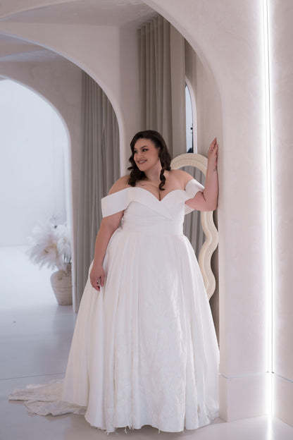 Woman in a white wedding dress standing in a bright, minimalistic room