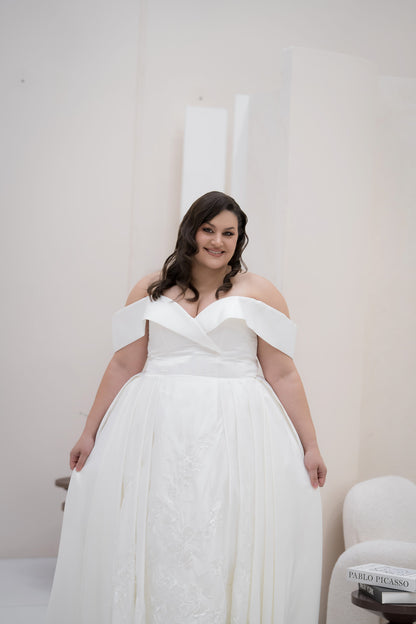 Woman wearing a white off-shoulder wedding dress indoors