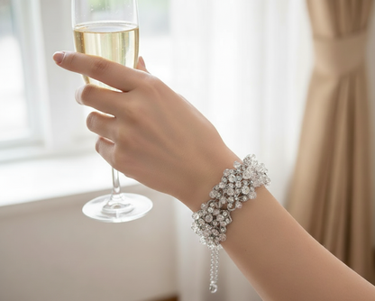 Hand holding a glass of champagne with a sparkling bracelet on a blurred background