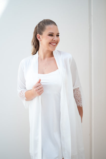 Woman wearing a white lace robe against a plain background