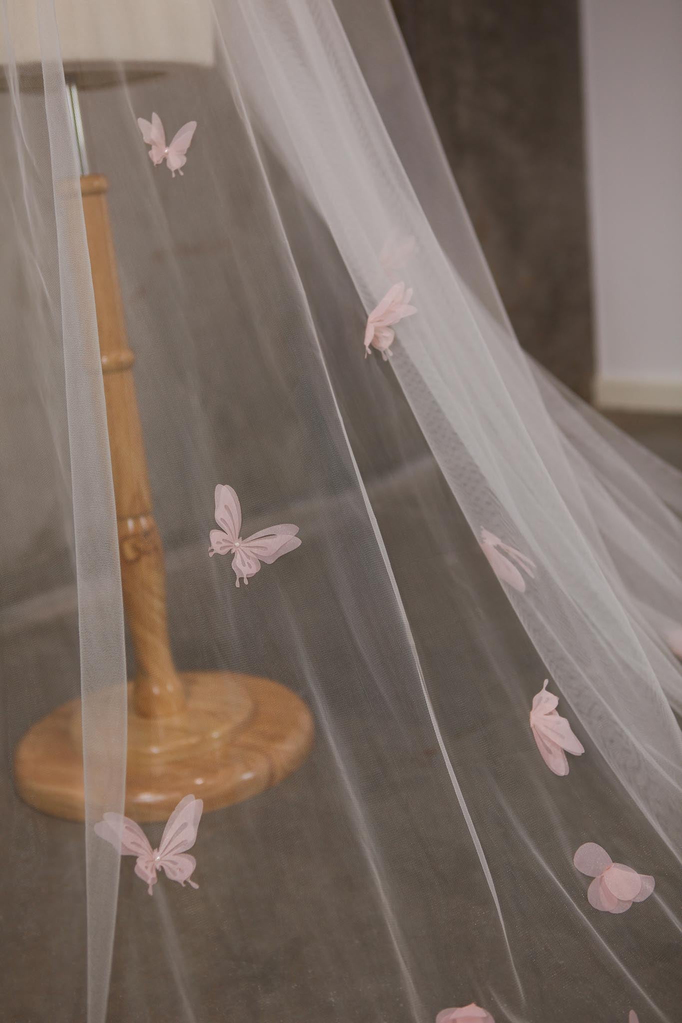Sheer fabric with butterfly embellishments on a stand against a neutral background