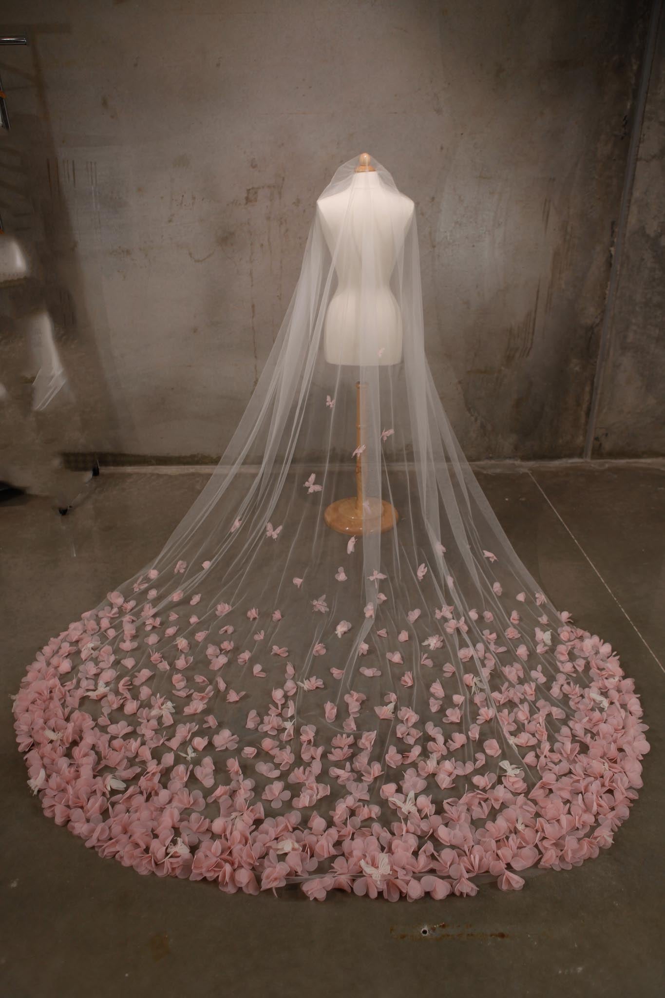 Veil with pink floral details on a mannequin against a plain background
