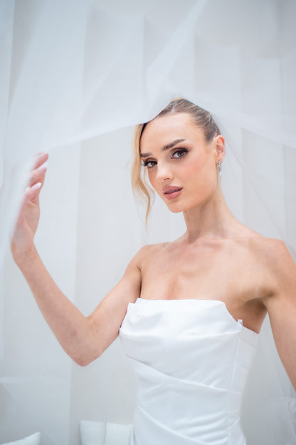 Woman wrapped in a white towel against a plain background