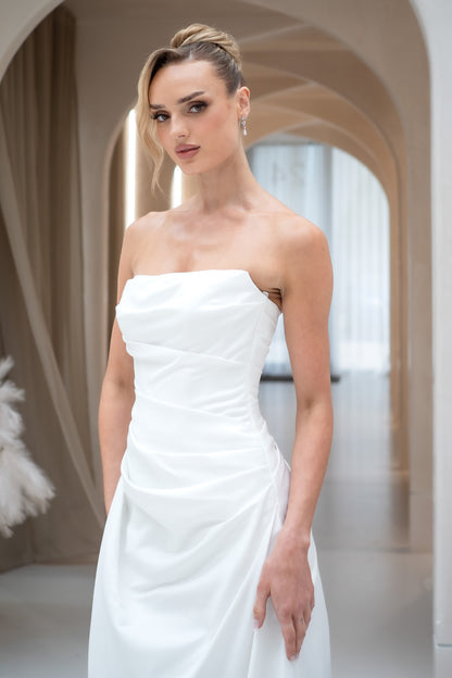 Woman wearing a strapless white wedding dress in an elegant indoor setting.