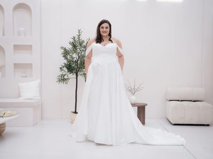 Woman in a white wedding dress standing in a minimalistic room with white walls and furniture