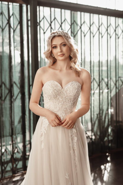 Woman in a white wedding dress standing in front of a decorative metal gate.