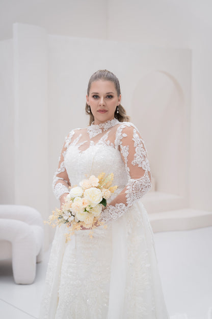 Bride in a white lace wedding dress holding a bouquet of flowers against a white background