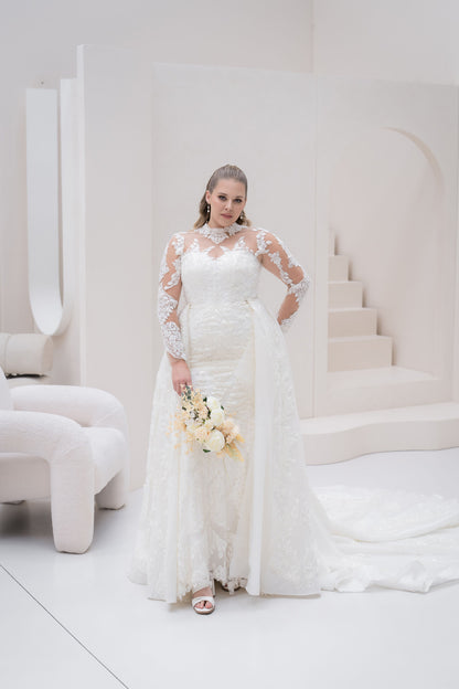 Woman in a white lace wedding dress holding flowers in a minimalistic setting