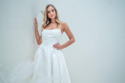 Woman wearing a white strapless dress against a plain background