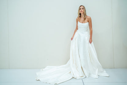 Woman wearing a white wedding dress against a plain background