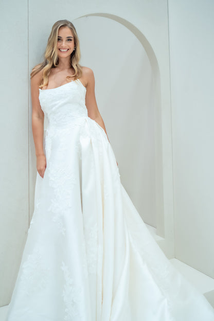Woman wearing a white wedding dress against a plain background