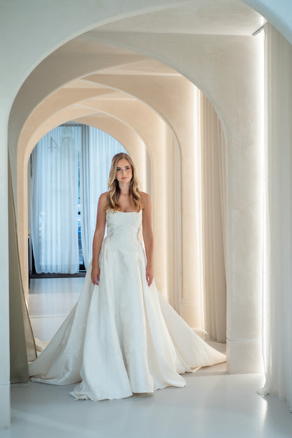 Woman in a white wedding dress standing in a modern architectural setting with arches.