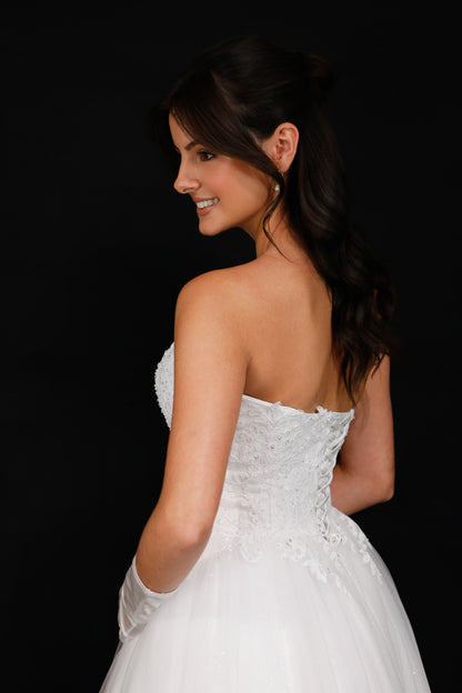 Woman in a white strapless dress against a black background