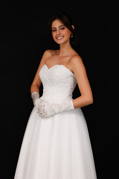 Woman in a white wedding dress with gloves on a black background