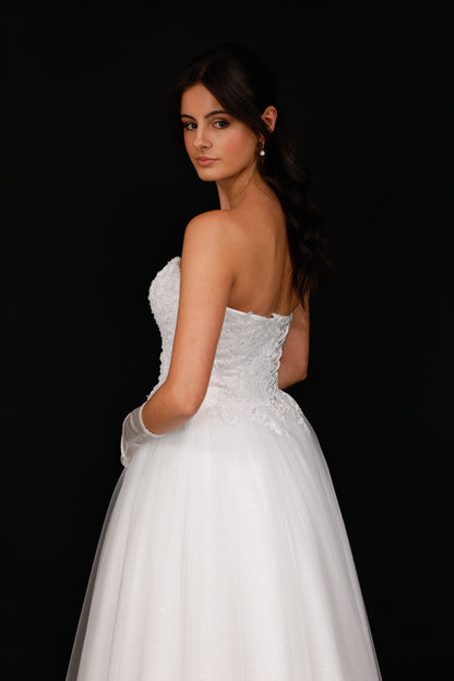 Woman in a white strapless gown against a black background