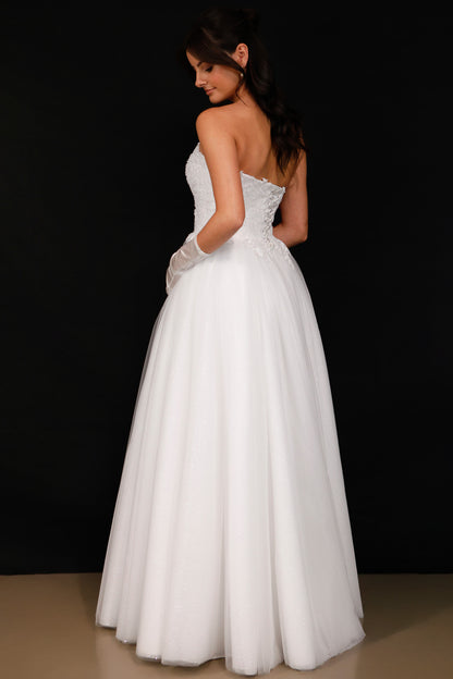 Woman wearing a white strapless wedding dress against a black background