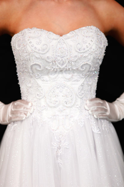 White strapless embroidered wedding dress with gloves on a black background