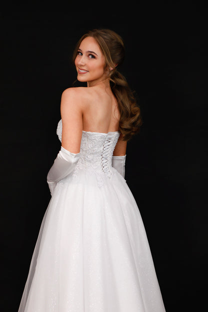 Woman in a white strapless gown with sheer overlay against a black background