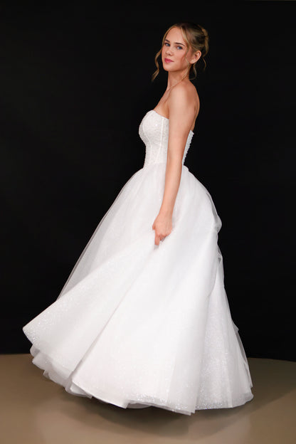 Woman wearing a white strapless gown against a black background