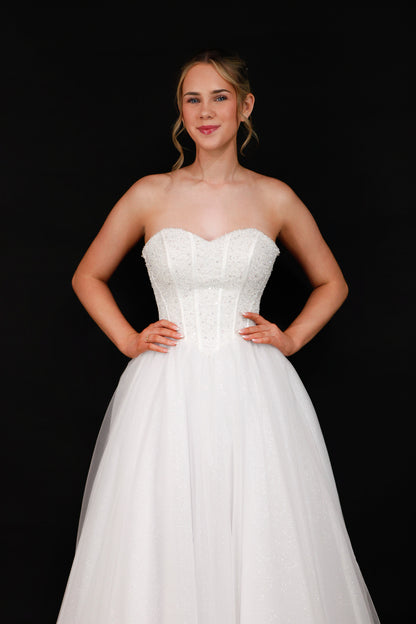 Woman wearing a white strapless gown against a black background