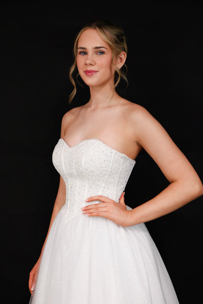 Woman wearing a strapless white wedding dress against a black background