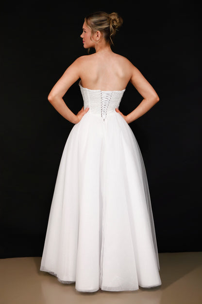 Woman wearing a white strapless gown against a black background