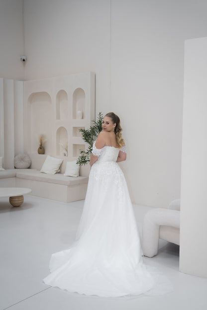 Woman in a white wedding dress standing in a stylish room with arches and decor.