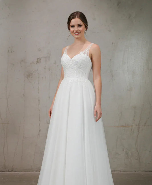 Woman wearing a white wedding dress against a plain background
