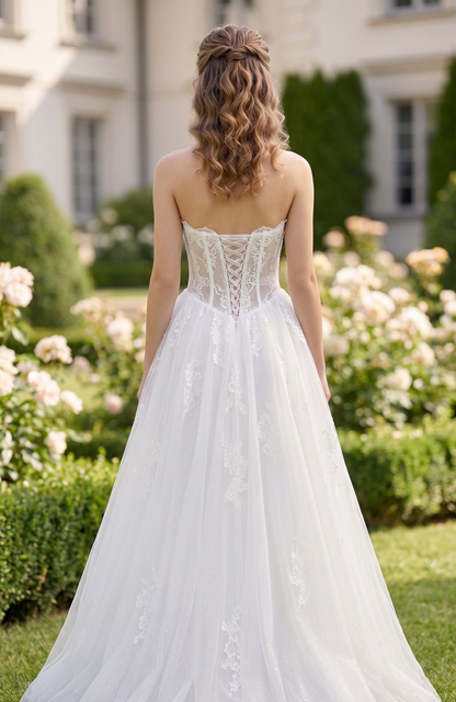 Woman in a white wedding dress standing in a garden with flowers and a building in the background