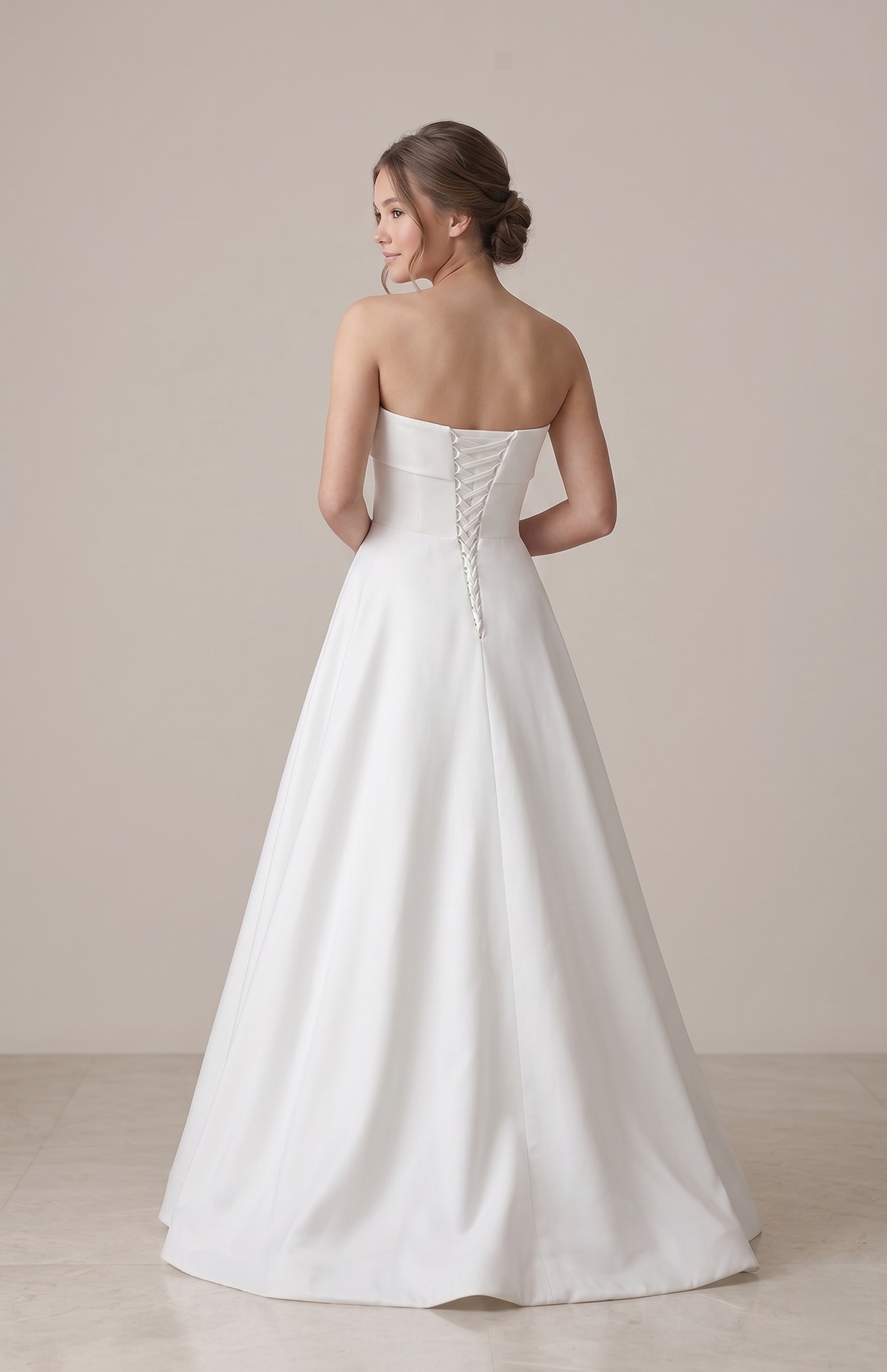 Woman wearing a strapless white wedding dress against a plain background