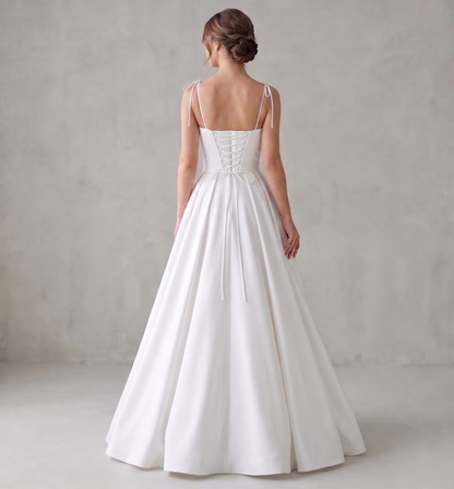 White wedding dress with thin straps on a plain background