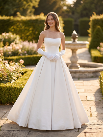 Woman in a white strapless gown with gloves standing in a garden.