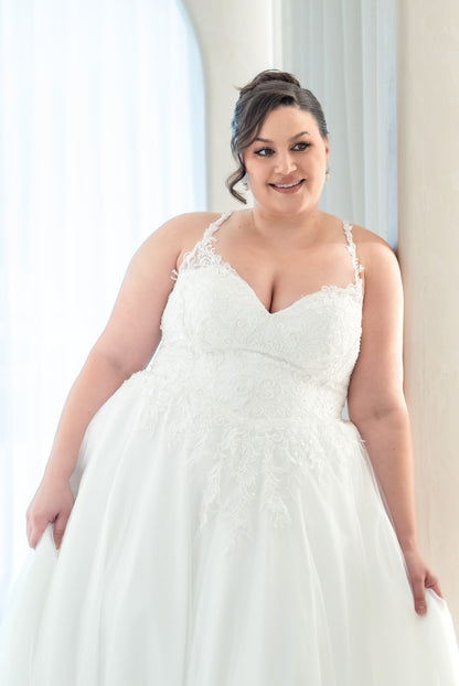 Woman wearing a white wedding dress indoors with a neutral background