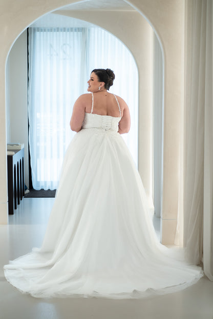 Woman in a white wedding dress standing in a doorway with curtains in the background
