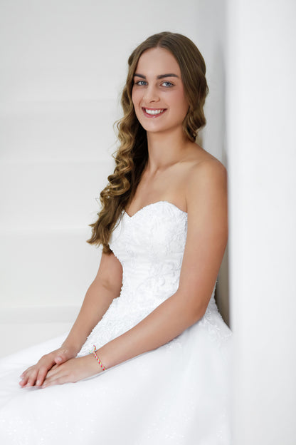 Woman in a white wedding dress against a plain background