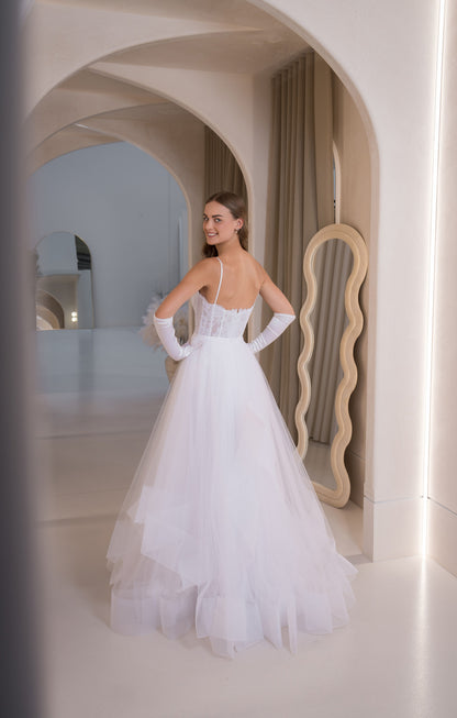 Woman in a white wedding dress standing in a stylish interior setting.