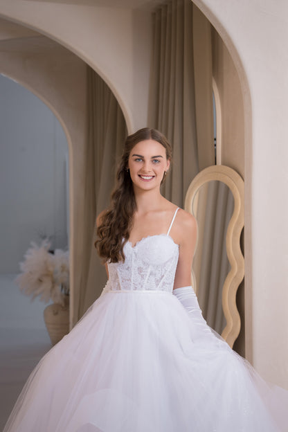 Woman in a white wedding dress standing in an elegant interior setting.